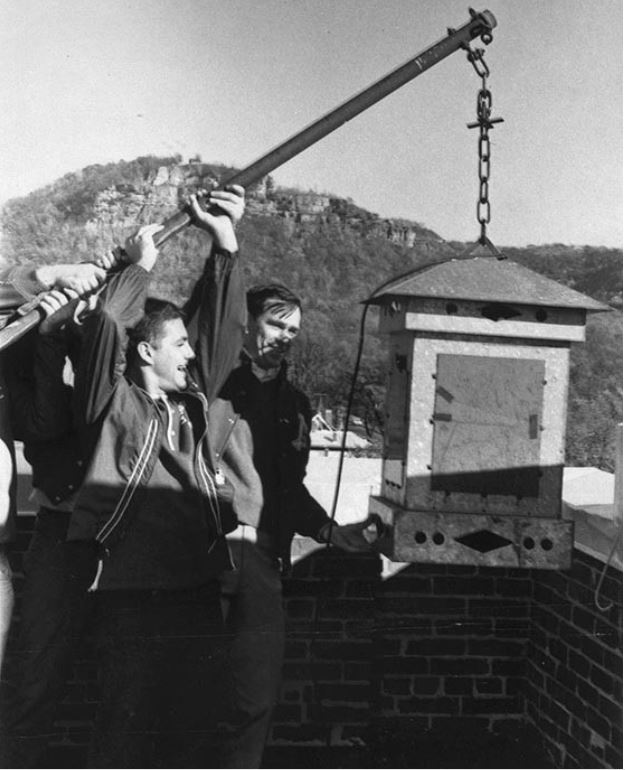 Orle Brown and James Christensen, center, members of Phi Sigma Epsilon, hang the lantern from Main Hall for the 1968 Homecoming festivities. The lantern burned throughout the weekend.