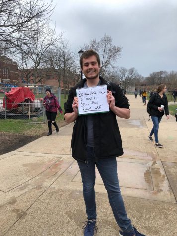 UWL student Jacob Larsen protesting while holding a sign that reads "If you don't have a uterus shut the fuck up"