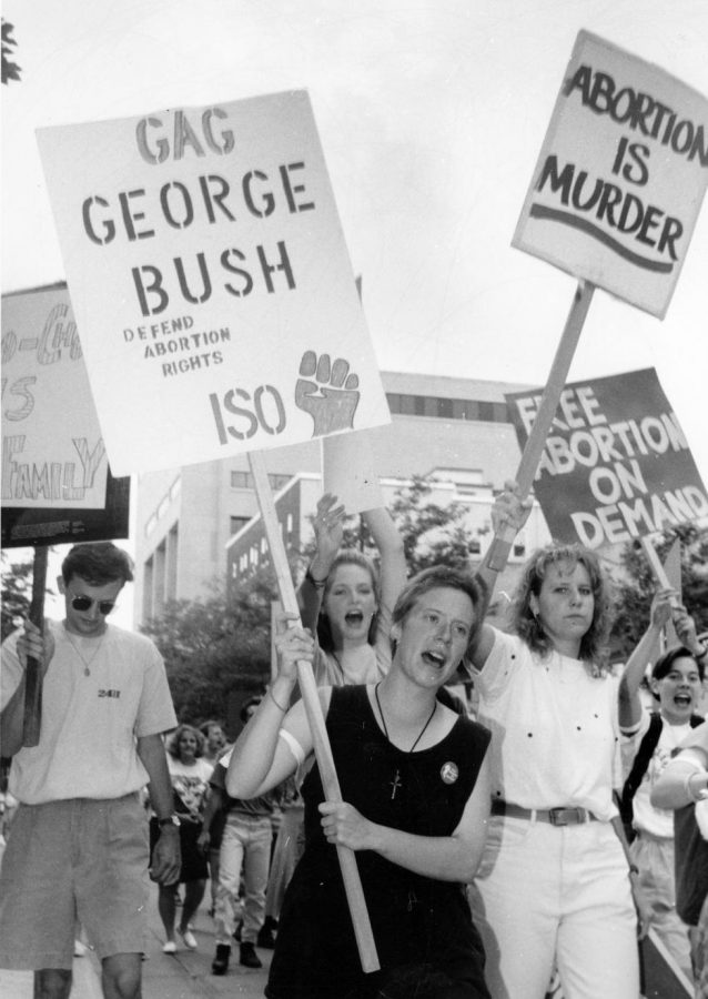 A woman holds a pro-life sign in the midst of several pro-choice signs.