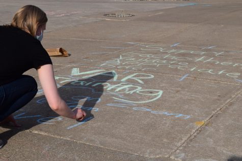 A photo of a student writing with chalk on campus.
